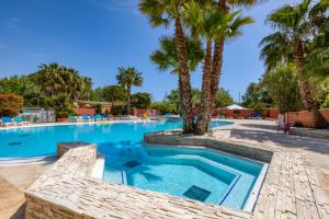 a swimming pool with palm trees in a resort at Bungalow in Agde