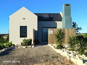 a white house with a fence in front of it at Silver Oaks Where The Clock Stops in Langebaan