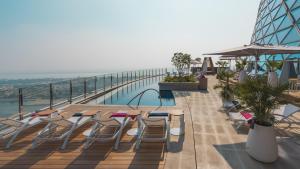 a balcony with chairs and a pool on a building at Andaz Capital Gate Abu Dhabi, By Hyatt in Abu Dhabi
