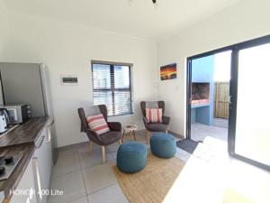 a kitchen with two chairs and a living room at Silver Oaks Where The Clock Stops in Langebaan
