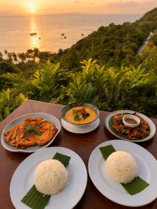 a table with plates of food on it with a view of the ocean at Ko Tao Paradise Resort in Ko Tao