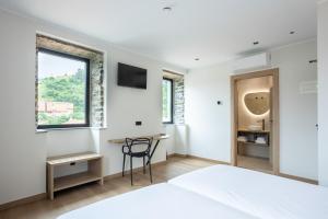 a bedroom with a bed and a desk and a window at Hotel Truita in Cangas del Narcea