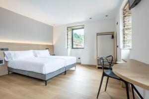 a bedroom with a bed and a desk and a table at Hotel Truita in Cangas del Narcea