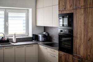 a kitchen with white cabinets and a black microwave at Sodyba Biruta in Tautrimai