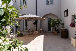 a patio with an umbrella and tables and chairs at "Corte Tedesco" - Apulian Luxury Suites in Brindisi