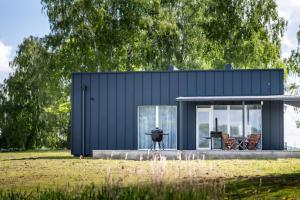 a black house with a table and chairs in a field at Sodyba Biruta in Tautrimai