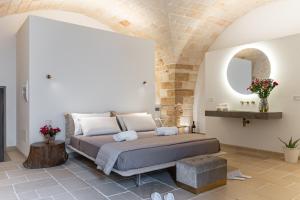 a bedroom with a large bed with a stone wall at "Corte Tedesco" - Apulian Luxury Suites in Brindisi