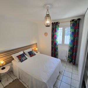 a bedroom with a white bed and a pendant light at Maison Lauret in Agde