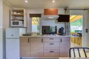 a kitchen with wooden cabinets and a white refrigerator at Bungalow in Agde