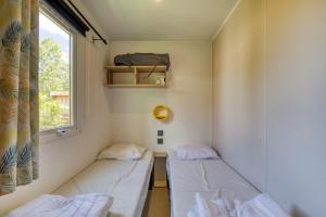 two beds in a small room with a window at Bungalow in Agde
