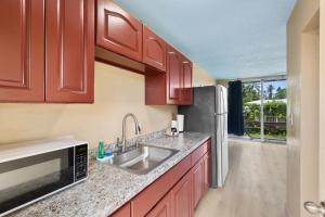 a kitchen with a sink and a refrigerator at Garden Balcony • Walk to Beach + Kitchen in Hilo