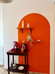a room with an orange wall with shelves and a table at Violahouse in Bari