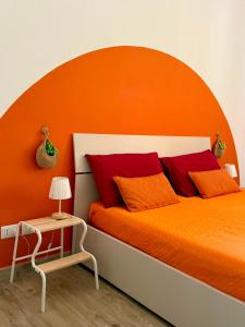 a bed with an orange headboard and red pillows at Violahouse in Bari