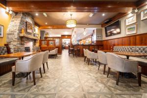 a restaurant with tables and chairs and a stone wall at Corr's Corner Hotel in Newtownabbey