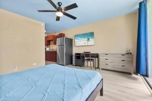 a bedroom with a bed and a kitchen at Garden Balcony • Walk to Beach + Kitchen in Hilo