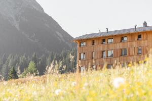 a building on a hill in a field of grass at Die Lecherin in Lech am Arlberg