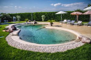 una piscina en un patio con sillas y sombrillas en B&B La Magia dei Sogni Relais, en Verona