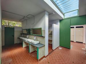a bathroom with a row of sinks and green walls at Camping Volterra in Volterra
