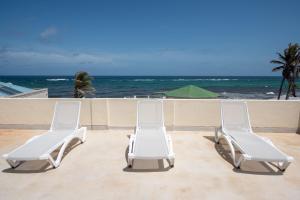 two white chairs sitting on a patio overlooking the ocean at Ocean Bliss Apartments in Christ Church