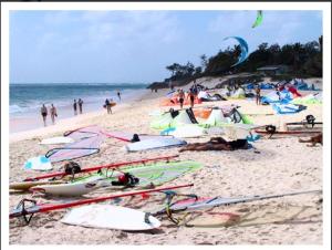 a group of people on a beach with kites and surfboards at Ocean Bliss Apartments in Christ Church +1 photo
