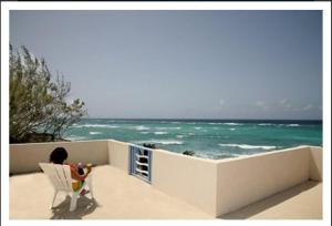 a woman sitting in a chair looking at the ocean at Ocean Bliss Apartments in Christ Church
