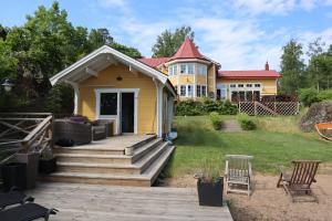 a yellow house with a porch and a yard at Sjöstugan in Tyresö