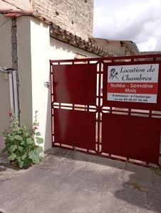 a red gate in front of a building with a sign at Le Platane in Brioux-sur-Boutonne