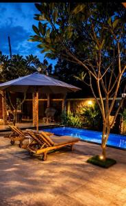 a group of tables and an umbrella next to a pool at Namali Private Villa in Gili Trawangan