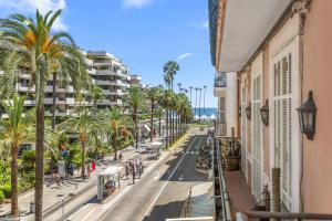 a street in the city with palm trees and buildings at Naomi Cannes in Cannes