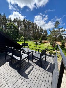 a deck with two benches and a table on it at Cozy studio in a horse ranch in Lieplaukė