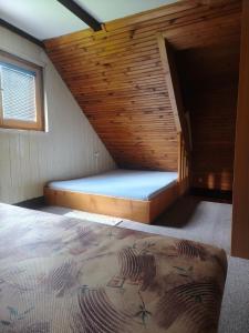 a bed in a room with a wooden wall at Chata Vanessa in Stránske