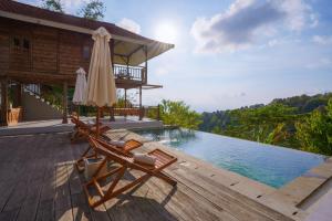 a pool with two chairs and an umbrella on a deck at Ocean & Mountain View Villa, Waterfalls, Munduk Eco-Luxe by Santrian in Munduk