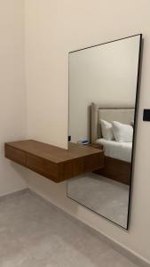 a mirror on a wall next to a bed at الارجان للشقق المفروشة in Al Nairyah