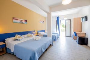 a hotel room with two beds and a television at Giostemar Rooms - Playa Grande in Scicli