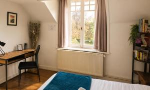 a bedroom with a bed and a desk and a window at LE MATIN CALME - Charme ancien - Vue canal in Dole
