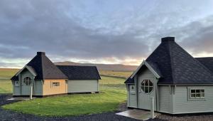 two houses in a field with grass and mountains in the background at Caerketton Cabin in Kirknewton
