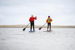 two people are standing on paddle boards in the water at Caerketton Cabin in Kirknewton