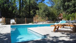 a pool with a bench and a table and chairs at Les Robinsons in Sillans-la Cascade