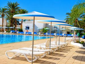a group of chairs and umbrellas next to a pool at Primavera Pool Paradise in Arona