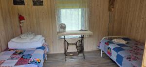 a room with two beds and a table and a window at Üleoja Saunaholiday in Kaagvere