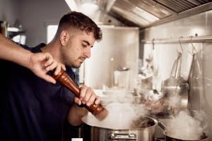 a man stirring a pot in a kitchen at Mila Malia Suites in Malia