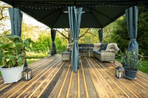 a deck with a couch and chairs under an umbrella at Jurta pod Blaníkem s wellnes in Chotýšany +53 photos