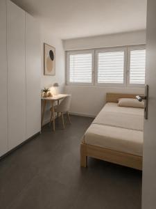a bedroom with a bed and a table and windows at Montebello in Bellinzona
