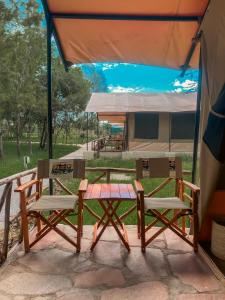 a picnic table and chairs under a tent at Emaamara camp in Narok
