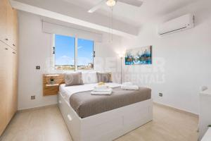 a white bedroom with a large bed and a window at Apartment El Breeze in Paralimni