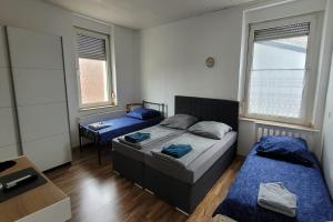 a bedroom with two beds and a table and two windows at Privileg - NewTime in Viersen