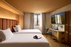 a hotel room with two beds and a desk and a window at You Hotel de France Valence - Handwritten Collection in Valence
