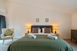 a bedroom with a large bed with two lamps and a chair at Pied-a-Terre Tomar in Tomar