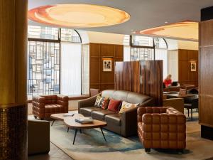 a lobby with a couch and chairs and a table at Sofitel Paris Arc De Triomphe in Paris