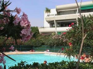 a swimming pool in front of a building with flowers at L'HERMITAGE - Studio moderne - Piscine - Ascenseur - Quart Golf in La Grande Motte